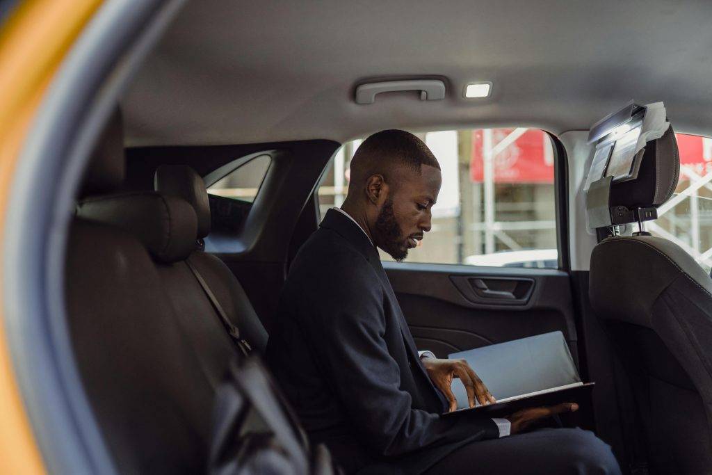pexels photo 13801858 13801858 A professional man in a suit reads documents while sitting in a car interior, conveying a business theme.